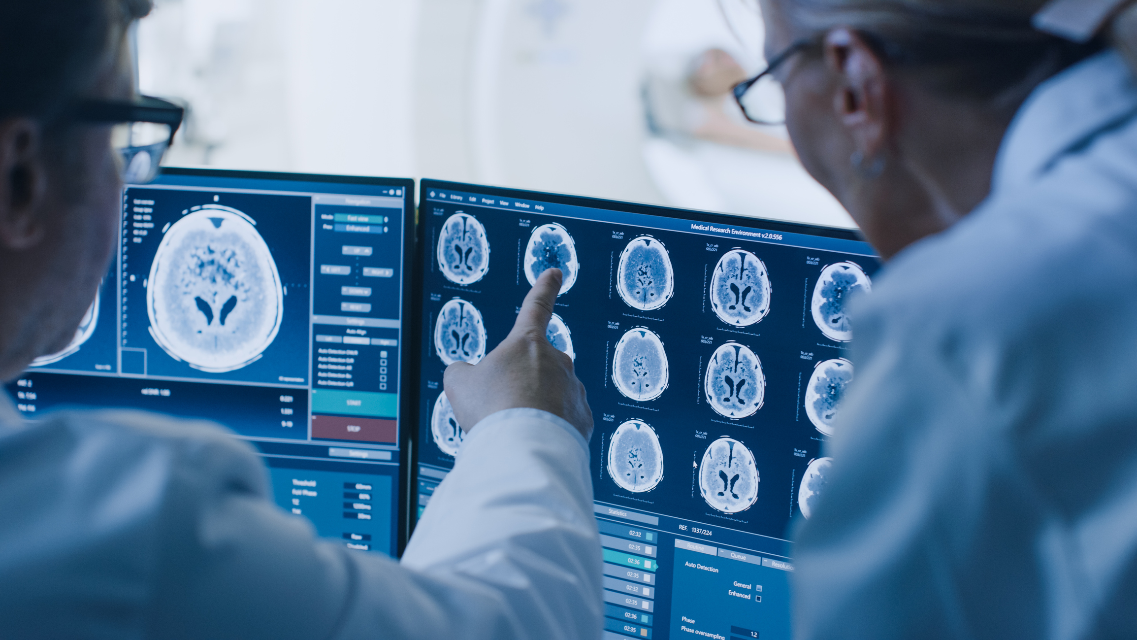 Two radiologists reviewing brain CT on large diagnostic monitors